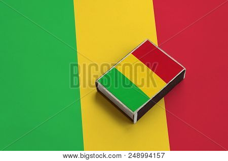 Mali Flag  Is Pictured On A Matchbox That Lies On A Large Flag.