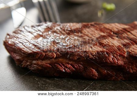 Hot Grilled Whole Alternative Steak or on Black Stone Background. Fresh Juicy Medium Rare Beef Grillsteak. Barbecue Meat Close Up