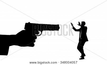 Silhouette Of Hand With Gun Threatening Minuscule Man, Life In Danger Death Risk