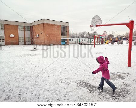 Child Girl In Red Pink Jacket Sliding On Ice Road On Her Feet On Schoolyard. Winter Fun Activity For