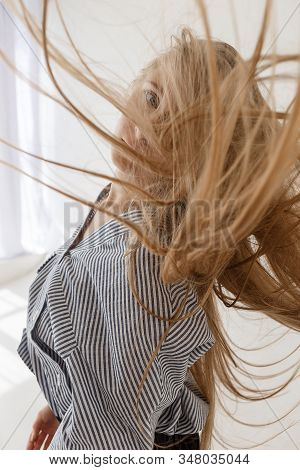 Young Pretty Teenage Girl In Striped Oversize Shirt Stands In Front Of White Studio Cyclorama And Lo