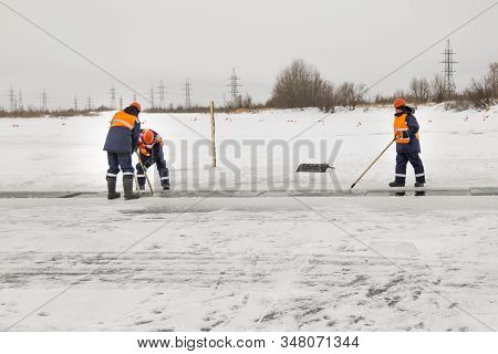 Workers Rafting Ice Blocks Along A Channel Cut Out By A Frozen Lake
