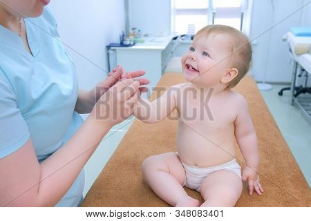 Professional Doctor Masseur Making Massage To Smiling Baby On Hand, Palm And Fingers In Clinic. Ther