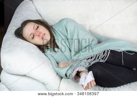 Sick, Unhealthy Woman With Temperature Lying On Sofa At Home Under Plaid.