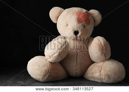 Toy Teddy Bear With Sticking Plasters On Grey Stone Table