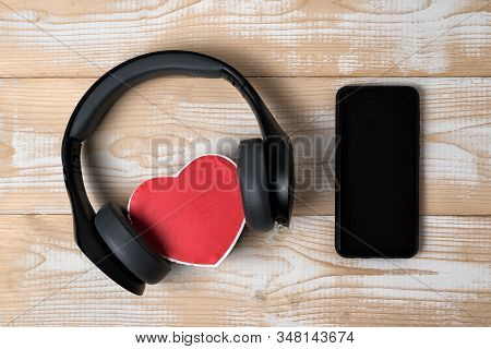 Full-size Wireless Headphones Pulled Over Small Red Heart-shaped Box And Smartphone On Light Brown W