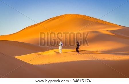 Merzouga, Morocco On February 24, 2018: Two Berbers In The Orange Sahara Desert, Merzouga, Morocco