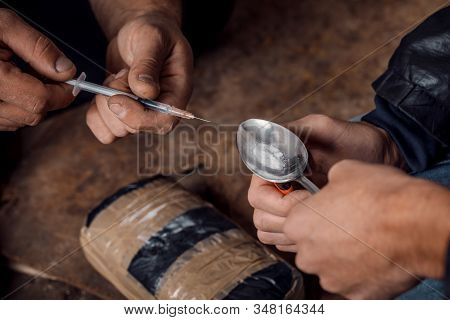 Two Shabby  Men Preparing Drug Injection In Slums.