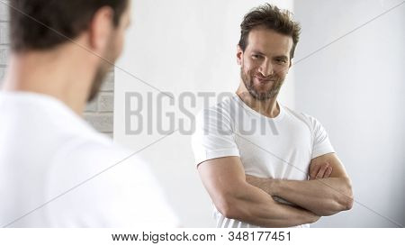 Satisfied With Beautiful Sports Figure Male Examining His Reflection In Mirror