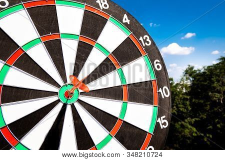 Dart Arrow Hit On Bulleyes Of Dartboard With Blue Sky, Planning New Business Target And Goals.