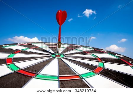 Dart Arrow Hit On Bulleyes Of Dartboard With Blue Sky, Planning New Business Target And Goals.