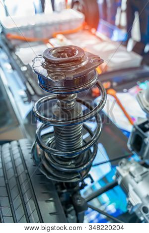 Closeup of light vehicle control arm, spring coil and shock absorber on electric system of eco car engine