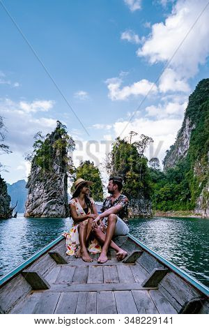 Couple Traveling By Boat Exploring Epic Limestone Cliffs In Huge Lake In Khao Sok National Park, Chi