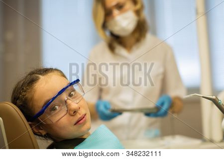 Portrait of teengirl wearing goggles sitting in a chair in dental office.