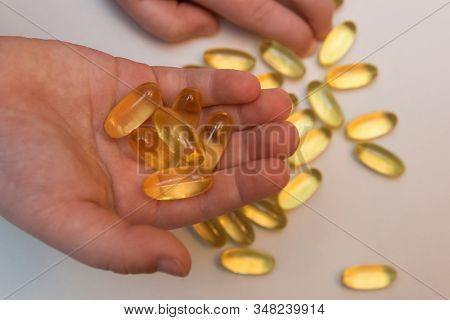 Vitaminen Omega 3 Oil In Capsules In Hand On Beige Background.