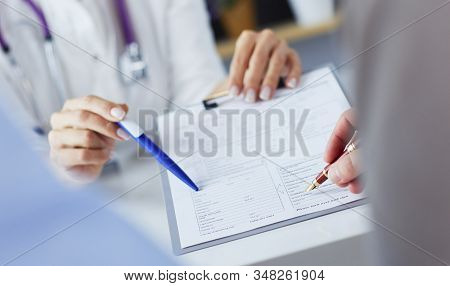Doctor And Patient Examining A File With Medical Records, She Is Sitting On A Wheelchair