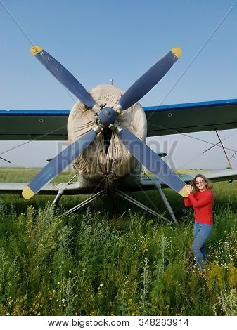 Woman Portrait In Front Of An Aircraft. Young Beautiful Woman With Red Jacket Stand In Front Of Olde