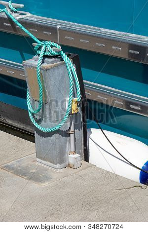 Green Roap Tied Down To Dock Area Near A Saltwater Marina