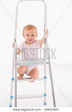 Linda niña de escalada en la escalera, sonriendo.