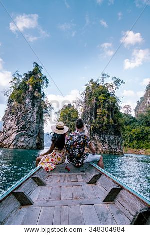 Couple Traveling By Boat Exploring Epic Limestone Cliffs In Huge Lake In Khao Sok National Park, Chi