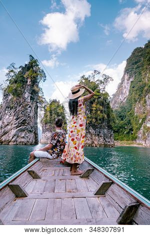 Couple Traveling By Boat Exploring Epic Limestone Cliffs In Huge Lake In Khao Sok National Park, Chi