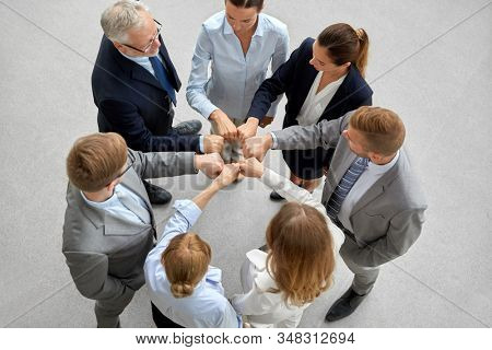 corporate, people and teamwork concept - happy business team making fist bump