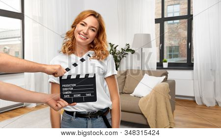 production, filmmaking and entertainment concept - happy woman or actress at studio casting and hands with clapperboard over home background