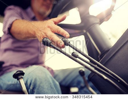 farming, agriculture and people concept - senior man driving tractor at farm