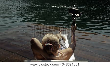 Woman Shooting On Handheld Film Gimbal Stabilization For Smartphone. Girl Lie Sunbed On Pier Make Se