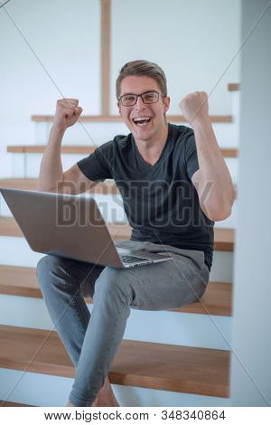 close up. happy young man with laptop sitting on steps
