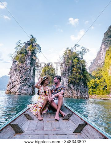Couple Traveling By Boat Exploring Epic Limestone Cliffs In Huge Lake In Khao Sok National Park, Chi