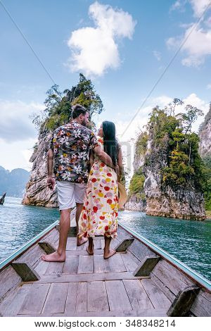 Couple Traveling By Boat Exploring Epic Limestone Cliffs In Huge Lake In Khao Sok National Park, Chi
