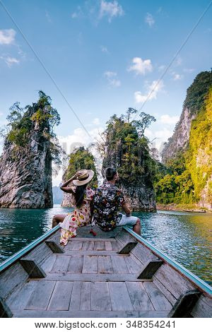 Couple Traveling By Boat Exploring Epic Limestone Cliffs In Huge Lake In Khao Sok National Park, Chi