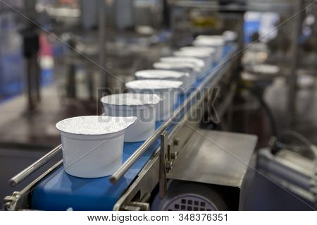White Yogurt Packages On A Production Line In A Dairy Farm.