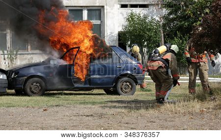 Firefighters Participate In A Training Where They Extinguish Fire From A Car Crashed Into Another Ve