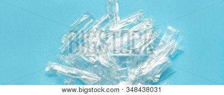 Pile Of Transparent Plastic Wrapping Rubbish On A Blue Background. Top View Of Many Plastic Wrapping