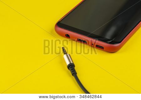 Close-up Jack Plug And A Cable With Phone On A Yellow Background, Top View.