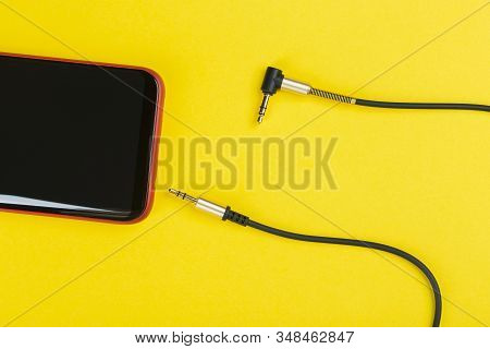 Close-up Jack Plug And A Cable With Phone On A Yellow Background, Top View.