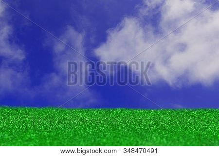 Grass On The Sky Background. Artificial Turf, White Clouds, Green And Blue Texture. Blurred Defocuse