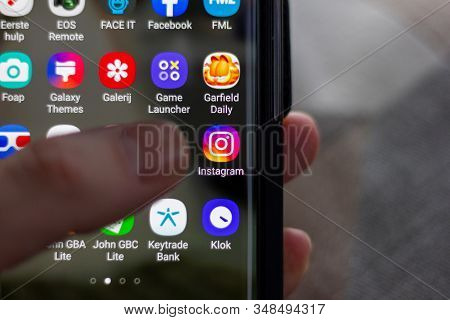 Brecht, Belgium - November 14 2019: A Portrait Of A User Holding His/her Phone With A Thumb Hovering