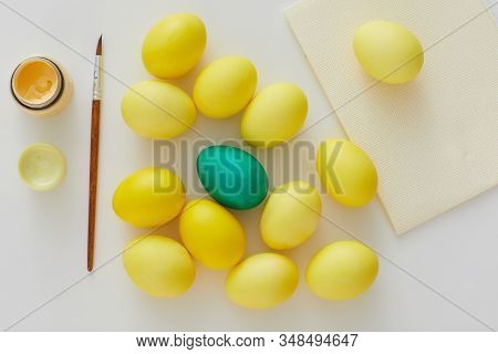 Above View Of Pastel Yellow Easter Eggs With Green Accent And Paint Brush Arraigned In Minimal Compo