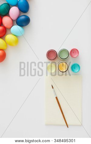 Above View Of Multi Colored Easter Eggs With Paint Supplies Arraigned In Minimal Composition On Whit