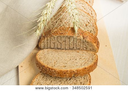 Sliced Slices Of Coarse Rye Bread On A Wooden Cutting Board With A Linen Cloth And Rye Ears, The Con