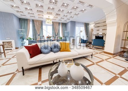 Living room overlooking a large white sofa. Pillows are presented as bright spots. In the foreground is a table with vases. The ceiling and floor are styled as squares.