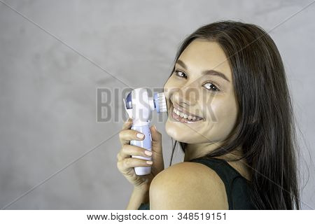 Young Pretty Woman Doing Skin Care Procedure. Cleaning Face With Machine Copy Space