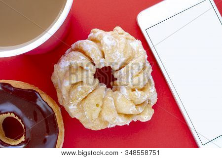 A Cup Of Coffee With A Chocolate Dip Donut And Honey Cruller Donut With A Smartphone