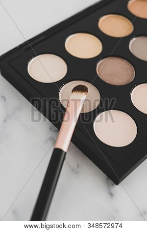 Close-up Of Brush On Top Of Eyeshadow Palette With Trendy Nudes And Bronzy Tones