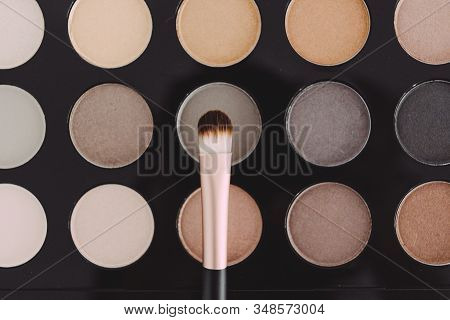 Close-up Of Brush On Top Of Eyeshadow Palette With Trendy Nudes And Bronzy Tones