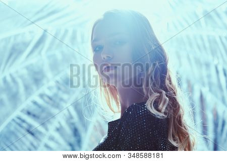 Beautiful blonde model girl in a dark sparkling dress with lurex posing in the light of softbox. Beauty, fashion.