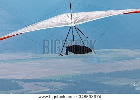 Flying Hang Glider Man In Action. Extremal Sportsman Enjoying His Recreational Journey To Creston, B